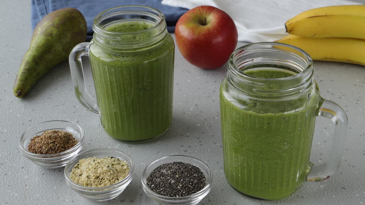 A nutritious green smoothie with apple, pear, and seeds in a cozy kitchen setting.